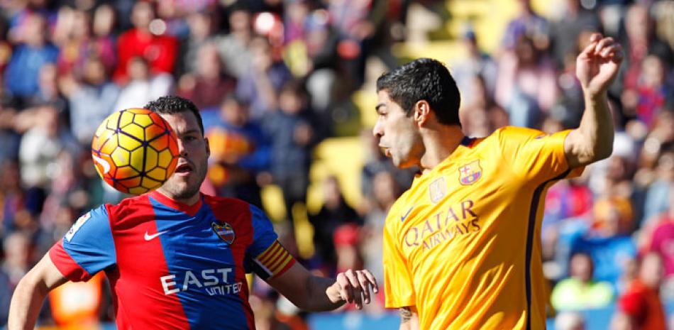 Luis Suarez, del Barcelona, a la derecha, lucha por controlar el balón con David Navarro, del Levante, durante el partido de la liga española de fútbol ayer.