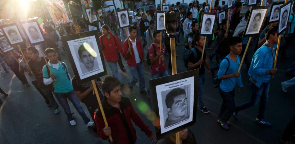 En esta foto de archivo del 26 de diciembre de 2015, familiares de los 43 estudiantes desaparecidos de Ayotzinapa marchan con fotos por la Ciudad de México.