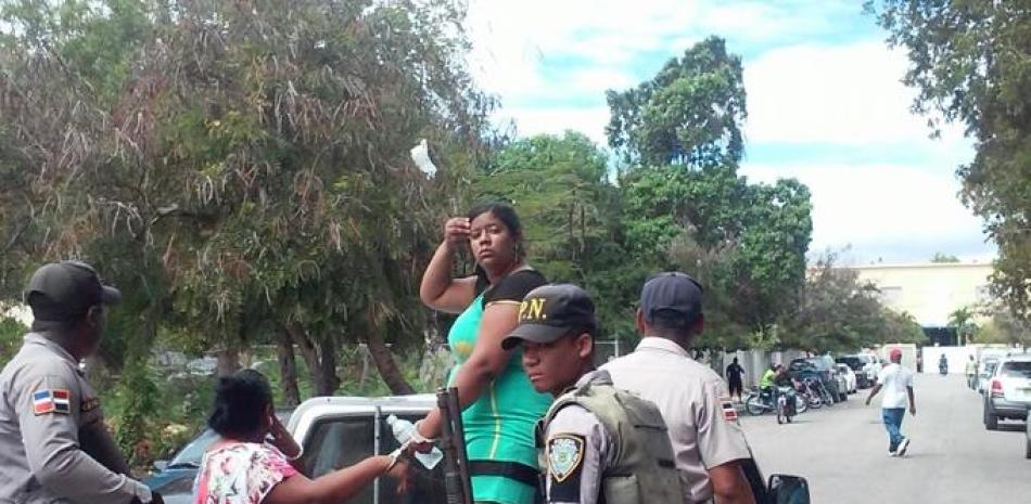 La agresora con blusa verde y de pie es conducida detenida por la Policía.
