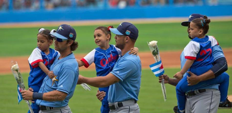 Integrantes de los Rays de Tampa Bay cargan niños y flores antes del partido de exhibición frente a la selección de Cuba ayer en el Estadio Latinoamericano en La Habana, partido que albergó a unos 50 mil fanáticos.