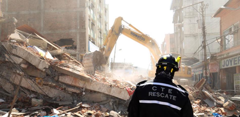 Escombros. Un rescatista observa a máquinas pesada retirar escombros de un edificio que colapsó en Portoviejo, ayer.
