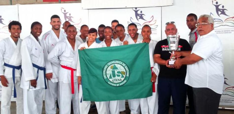 El presidente de la Federación de Karate, José Luis Ramírez, entrega el trofeo al equipo ganador UTESA y al ocupante del segundo lugar UNAPEC, en el Torneo Nacional de Karate universitario.