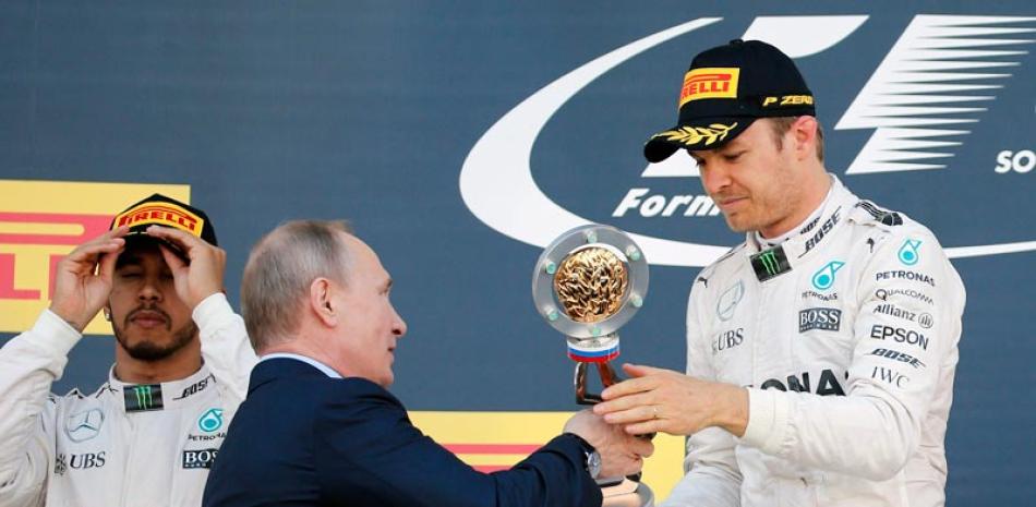 Nico Rosberg, de Mercedes, recibe su trofeo como ganador del Gran Premio de Fórmula Uno en Rusia de manos del presidente de ese país Vladimir Putin en el podio del circuito de automovilistmo de Sochi ayer.