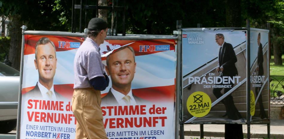 En esta imagen, tomada el 19 de mayo de 2016, un hombre pasa por delante de carteles electorales de Alexander van der Bellen, candidato a presidir Austria y exlider de los Verdes (derecha), y Norbert Hofer, aspirante del ultraderechista Partido de la Libertad (FPOE), en Vienea, Austria. (Foto AP/Ronald Zak)