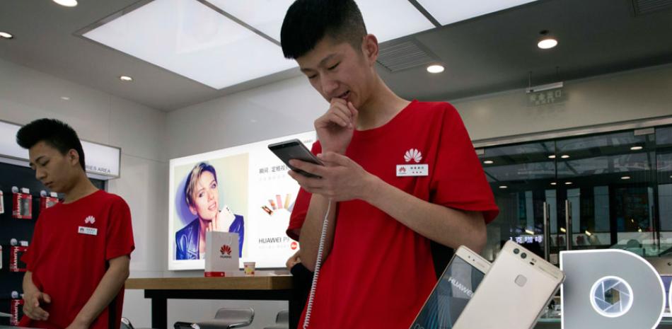 En esta imagen del 13 de mayo de 2016, agentes de venta chinos esperan a clientes en una tienda minorista de Huawei en Beijing, China. Foto AP