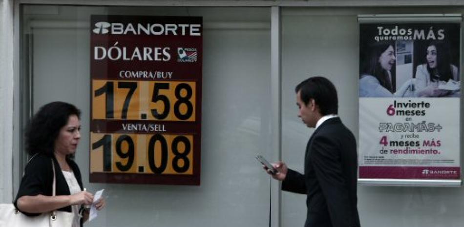 Mexicanos caminan frente a un banco donde la cotización del dólar ha alcanzado los $19.08 pesos mexicanos en Puebla (México). Tras el “Brexit”, donde el Reino Unido ha votado a favor de su salida de la Unión Europea.