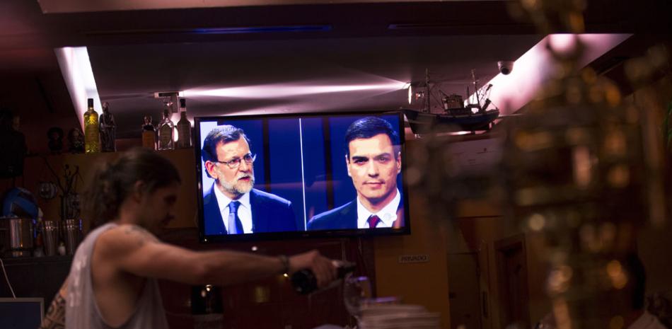 Mariano Rajoy, a la izquierda, y el líder de los socialistas Pedro Sánchez son vistos en el televisor de un bar cuando realizaban un debate antes de las elecciones en Madrid el 13 de junio del 2016. / AP