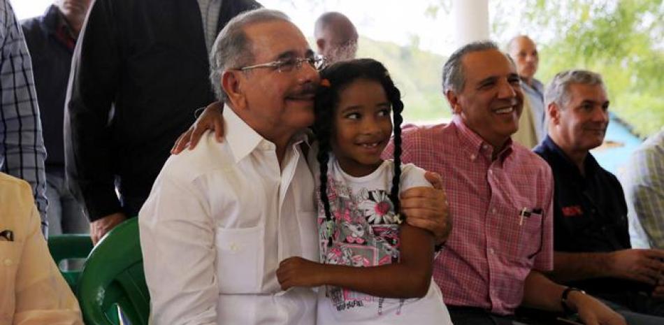 El presidente Danilo Medina aparece con una niña durante la visita sorpresa que realizó ayer al municipio de Hondo Valle. A su lado, los ministros José Ramón Peralta y Gonzalo Castillo.