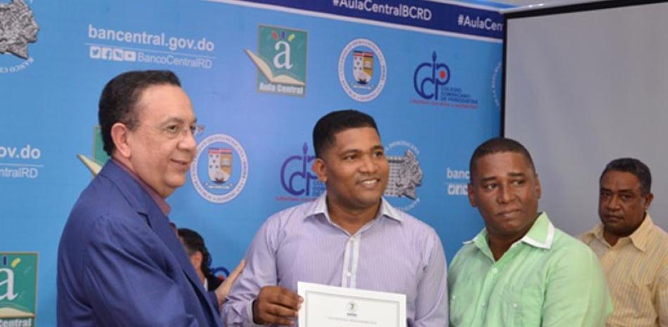Acto. El gobernador del Banco Central, Héctor Valdez Albizu, entrega certificado al periodista Geuris Guzmán.
