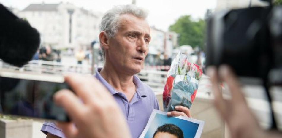 El padre de una víctima muestra una fotografía de su hijo cerca del centro comercial donde se produjo un tiroteo en el que murieron nueve personas el día anterior, el sábado en Múnich, Alemania