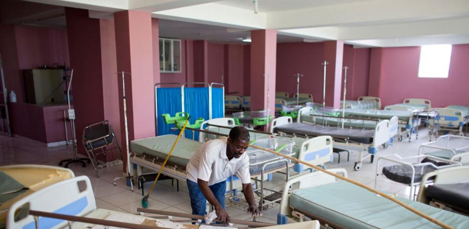 En esta imagen del 15 de julio de 2016, un trabajador mueve una camilla mientras barre el ala vacía patología en el hospital de La Paix en Delmas, Haití.