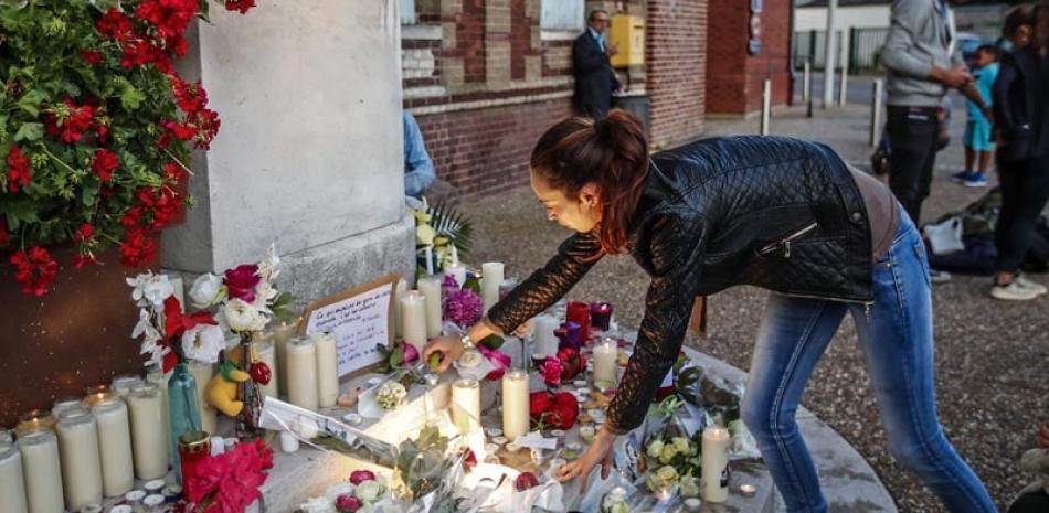 Altar. Una mujer enciende velas en un altar improvisado ayer, en frente de la alcaldía luego de un incidente en la iglesia Saint-Etienne-du-Rouvray, cerca a Rouen.