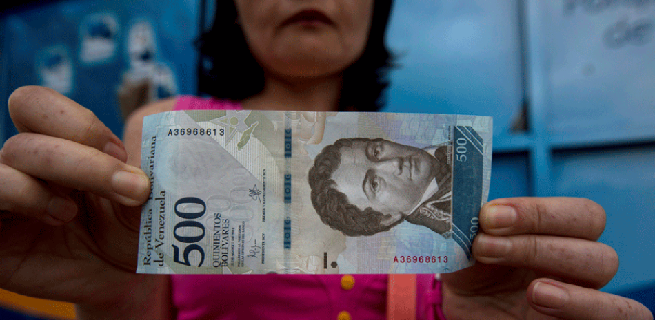 Un cliente muestra un billlete nuevo de 500 bolívares fuera de un banco en Caracas, Venezuela, el lunes 16 de enero de 2017. (AP Foto/Fernando Llano)