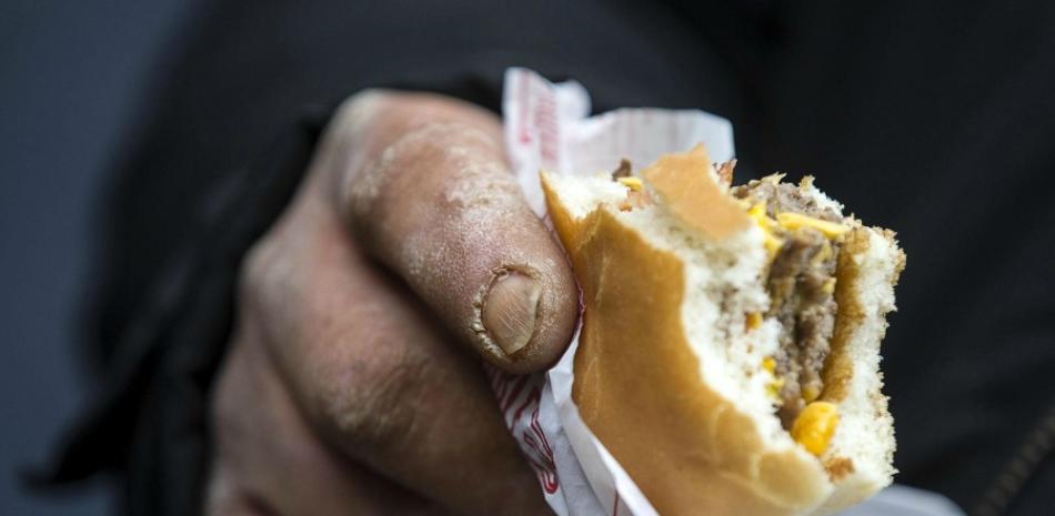 Un indigente come una hamburguesa de McDonald's cortesía del recién abierto local de comida rápida en Roma, Italia. (EFE/Angelo Carconi)