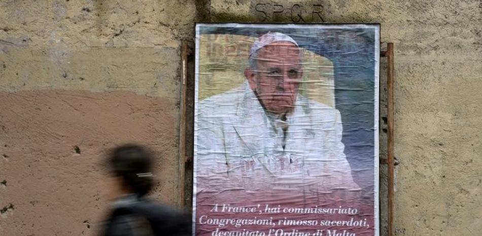 Una mujer pasa el 6 de febrero de 2017 junto a un cartel contra el papa Francisco, cuya proliferacio´n en el centro de Roma es investigada por la polici´a italiana. AFP