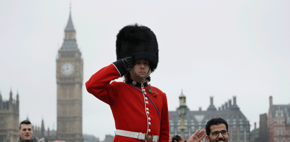 Un hombre posa para una fotografía junto a un hombre en zancos disfrazado de Guardia Real británico, en Westminster, Londres, Reino Unido, hoy, 8 de febrero de 2017.