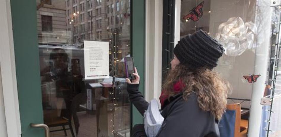 WASHINGTON (ESTADOS UNIDOS).- Una mujer hace una fotografía al anuncia del restaurante del 'Oyamel Cocina Mexicana' cerrado en solidaridad con la protesta 'Día sin inmigrantes' en Washington, Estados Unidos. EFE/Michael Reynolds