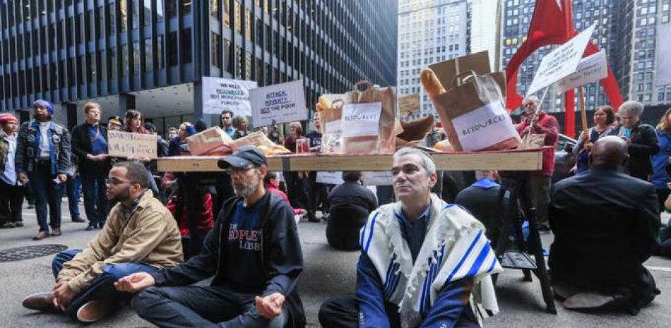 Desobediencia. Manifestantes participan en un acto de desobediencia civil al bloquear el tránsito en la calle Dearborn ayer, durante la protesta ResistTrumpTuesday, en Chicago, Illinois.