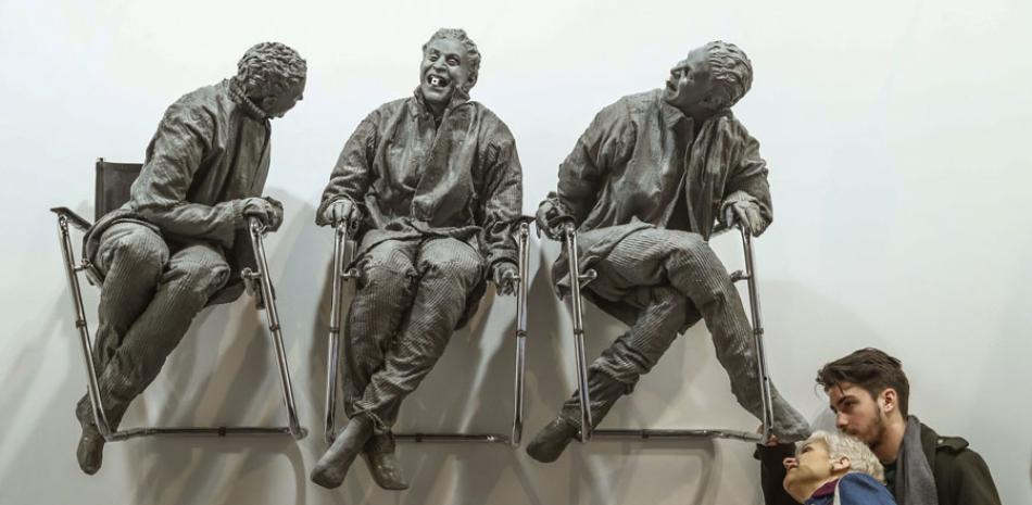 Dos personas observan la escultura “Three laughing at one” (2000), del artista español Juan Muñoz.