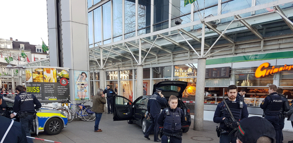 Un automóvil está delante de una tienda, custodiado por policías en Heidelberg, Alemania, el sábado, 25 de febrero del 2017. Un hombre al parecer embistió con su auto un grupo de peatones en una plaza en el centro de Heidelberg, hiriendo a tres personas, y escapó, hasta que fue herido pde bala por la policía. (R. Priebe/PR-Video/dpa via AP)