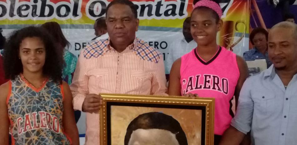 El ministro de Deportes Danilo Díaz Vizcaíno recibe un cuadro con su retrato del pintor Wagner Matos, quien lo entregó en persona junto a las jóvenes Yonairy Ventura y Mía Liberato.