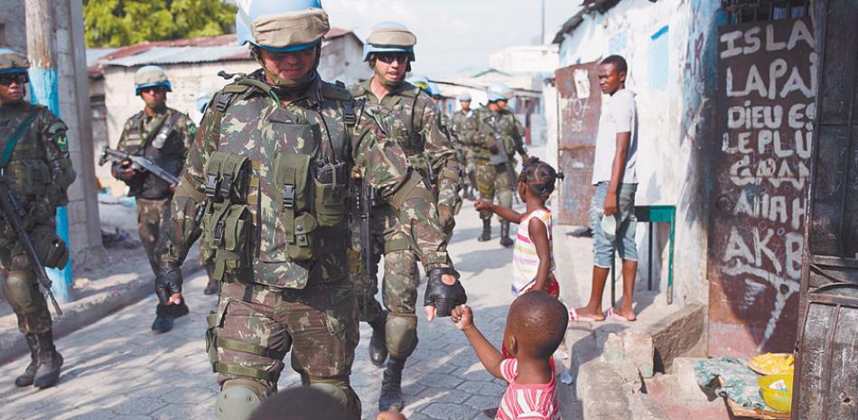 Saludo. Soldados brasileños de la ONU saludan a niños durante una patrulla por la favela Cité Soleil en Puerto Príncipe, el 22 de febrero pasado.