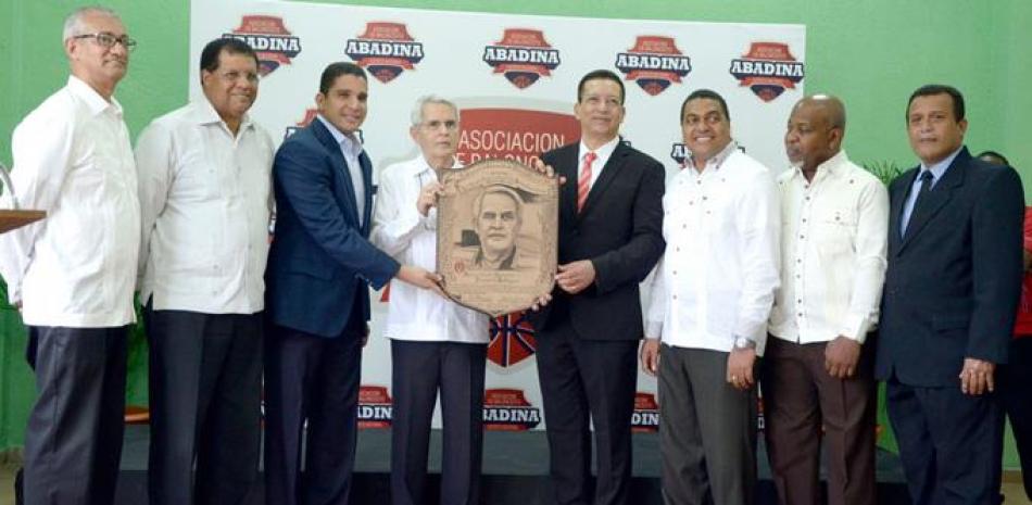 Humberto Rodríguez, quien está dedicado el próximo torneo de baloncesto superor distrital, recibe su placa de manos de Rafael Uribe, presidente de la Fedombal y Johnny Jones, secretario general de la Liga Municipal Dominicana.