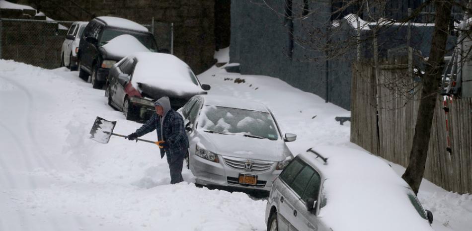 Labor. Un hombre retira la nieve alrededor de su vehículo en la Calle William, luego del paso de la tormenta por Nueva York, ayer.
