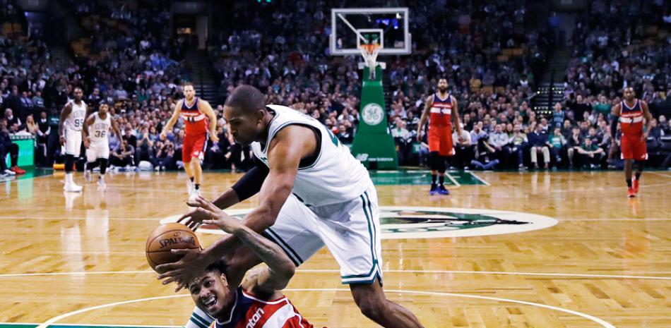Kelly Oubre Jr., de Washington, cae al tabloncillo mientras pierde el control del balón frente a Al Horford, de los Celtics de Boston, durante la segunda mitad del partido de anoche en el baloncesto de la NBA.