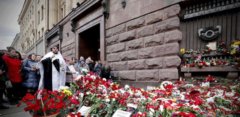Un sacerdote ortodoxo realiza una oración mientras varias personas rinden homenaje a las víctimas del atentado en el metro de San Petersburgo del pasado 3 de abril en la estación Tejnologuícheskiy Institut, en San Petersburgo, Rusia, hoy, 5 de abril de 2017. EFE/Anatoly Maltsev