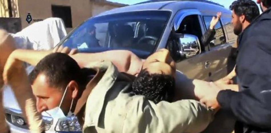 En esta escena extraída de un video proporcionado el martes 4 de abril por la agencia de noticias Qasioun, y que coincide con información independiente de AP, un hombre sirio carga sobre su espalda a un hombre afectado por un posible ataque químico, en la localidad de Khan Sheikhoun, en la provincia de Idlib, Siria. (Qasioun News Agency, via AP)