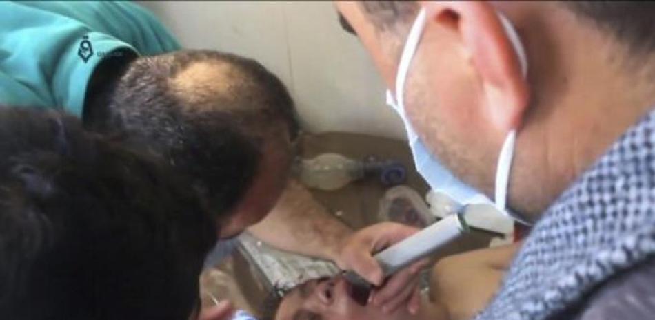 En esta escena extraída de un video proporcionado el martes 4 de abril por la agencia de noticias Qasioun, y que coincide con información independiente de AP, muestra a un médico sirio atendiendo a un chico tras un posible ataque químico, en la localidad de Khan Sheikhoun, en la provincia de Idlib, Siria. (Qasioun News Agency, via AP)