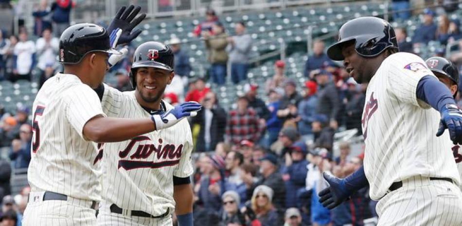 Miguel Sano, de Minnesota, saluda a Eddie Rosario, izquierda, y a Eduardo Escobar, a quienes remolcó tras disparar un triple con las bases llenas en el séptimo inning del partido contra Kansas.