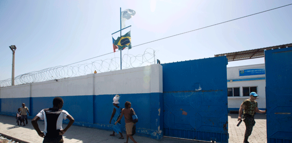 En esta fotografía del 16 de agosto de 2016, un cazco azul brasileño abre una puerta grande en una base de la ONU en el barrio pobre de Cite Soleil en Puerto Príncipe, Haití.