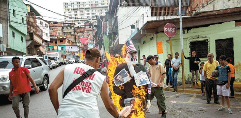 Caracas. Un grupo participa en la quema de judas con un muñeco con una fotografía del presidente de Estados Unidos, Donald Trump, y una bandera de ese país como sombrero.