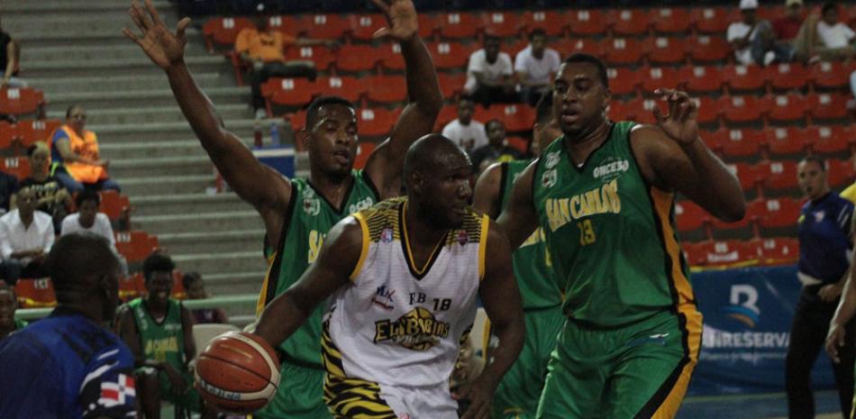 Juan Araujo, del Rafael Barias, maneja el balón ante la defensa de Claudio Calero y Joey de la Rosa, de San Carlos, en acción del partido de ayer en el baloncesto superior distrital.