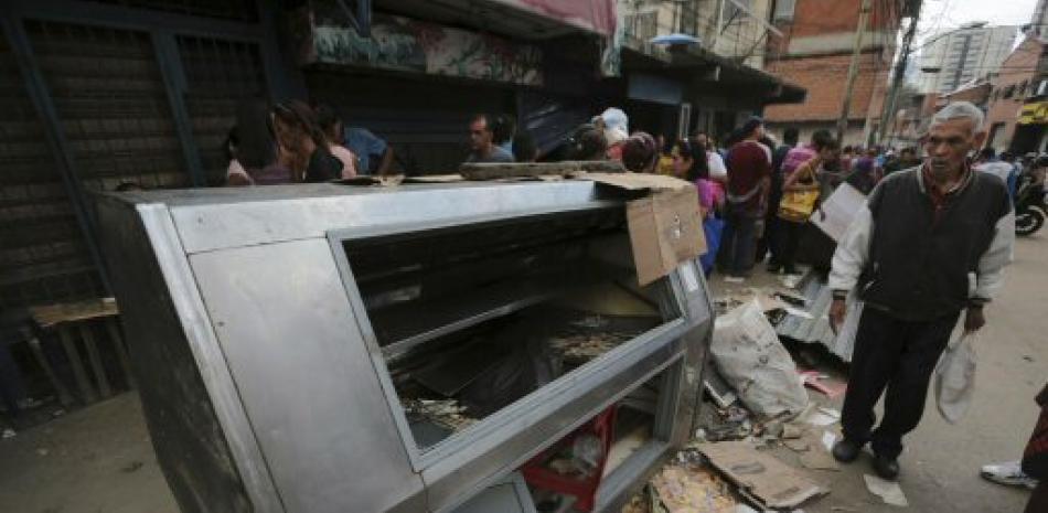 Un peatón pasa junto a un refrigerador destruido durante un saqueo la noche anterior en el barrio El Valle en Caracas, Venezuela, el viernes 21 de abril de 2017.