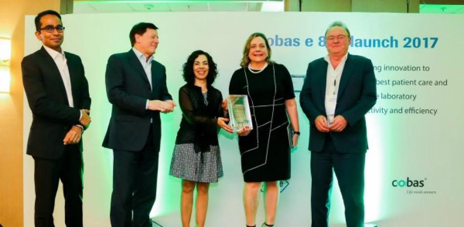 Patricia León recibe el reconocimiento por ejecutivos de Roche.