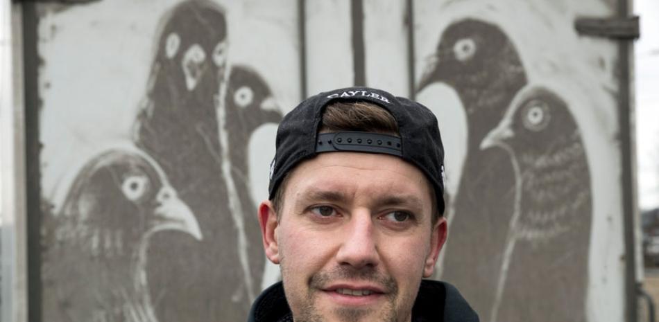 El artista ruso Nikita Golubev conversa con la AP frente a un dibujo de palomas que hizo en la parte trasera de un camión sucio en Moscú. Los camiones mugrientos que recorren las polucionadas calles de la capital rusa han inspirado un nuevo tipo de arte callejero.