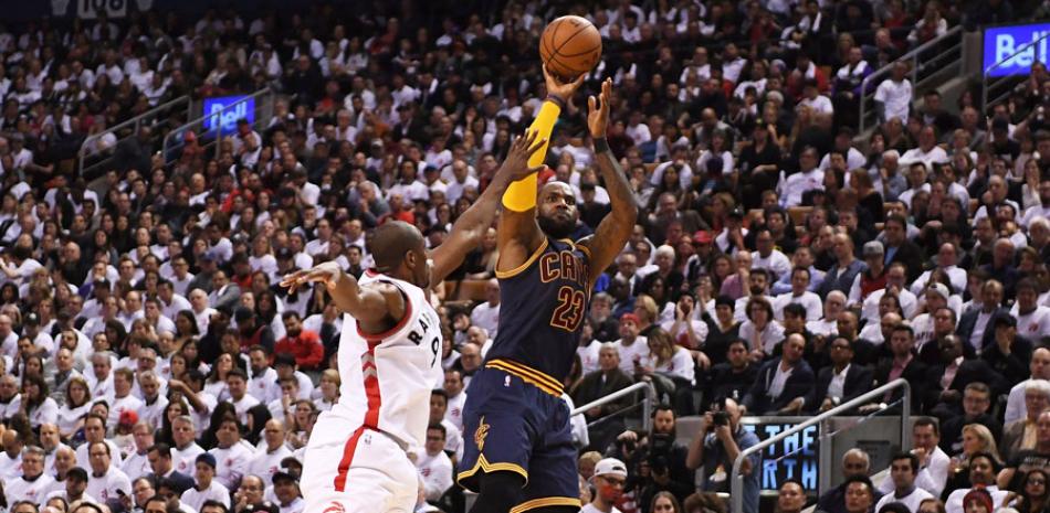 LeBron James, de los Cavaliers de Cleveland, se apresta a lanzar el balón sobre la defensa de Serge Ibaka, de los Raptors de Toronto, durante la segunda mitad del partido de la NBA anoche en la semifinal de la Conferencia del Este en el Air Canada Centre.