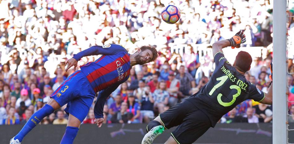 Gerard Piqué, del Barcelona, intenta anotar un gol con la cabeza ante la defensa del portero del Villarreal, Andrés Fernández.