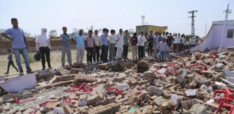 Unas personas observan los escombros dejados por el derrumbe de una enorme pared que cayó sobre los invitados de una boda en Bharatpur N.K. Gupta, en el oeste de India dejando al menos 24 muertos, el jueves 11 de mayo de 2017. (AP Foto)