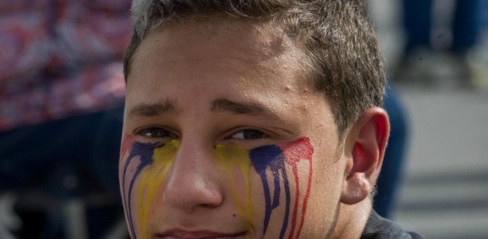 Un manifestante simula lágrimas con pintura de los colores de la bandera nacional durante el denominado "Gran plantón nacional" convocado por la oposición ayer en Caracas (Venezuela). (EFE/Miguel Gutiérrez)