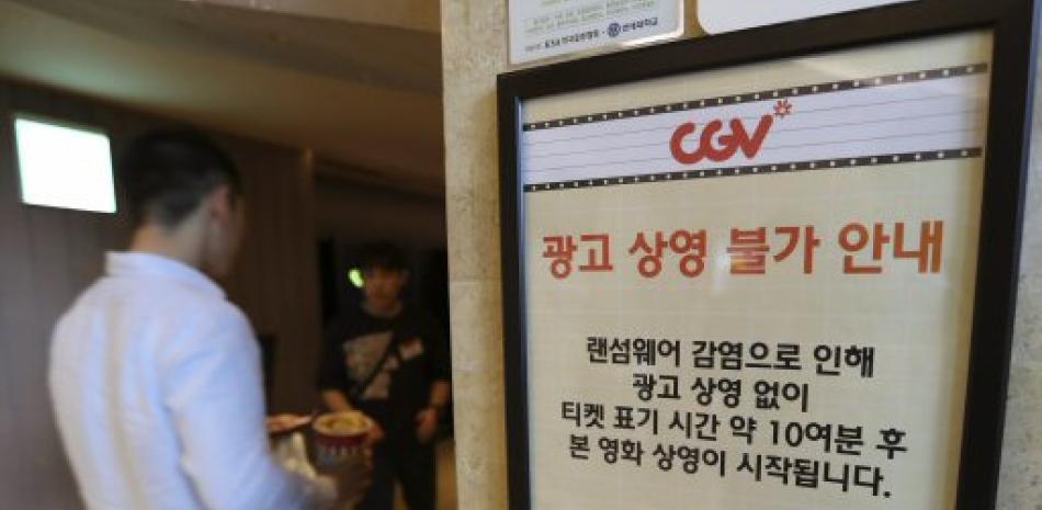 Un cliente pasa junto a un aviso sobre el ataque informático de "ransomware" en el teatro CGV en Seúl, Corea del Sur, el 15 de mayo de 2017. (AP Foto/Lee Jin-man)