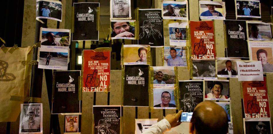 Mural. Un mexicano toma fotos de docenas de periodistas asesinados, frente a una verja cerca del Ministerio de Interior, ayer.