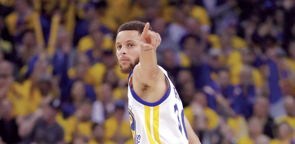 Stephen Curry señala a su banca luego de anotar dos puntos en el triunfo de los Warriors anoche.