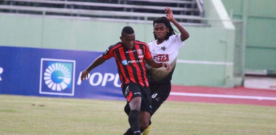 Junior Delvba del Moca FC defiende un jugador del Bauger FC.