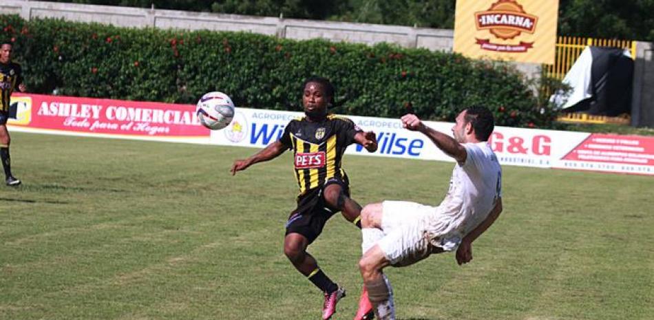 Miguel Ramírez, de Moca busca hacer ofensiva ante la fuerte oposición de un jugador de los Delfines en acción de la Liga Dominicana de Fútbol.
