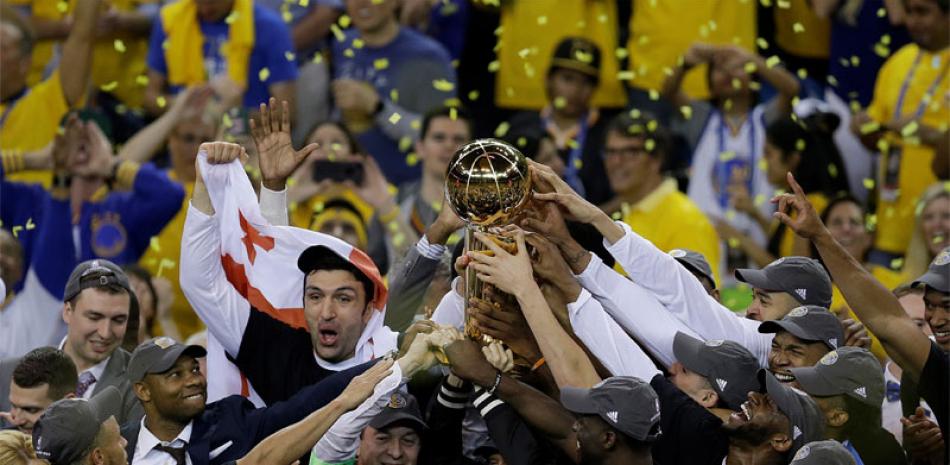 JÚBILO. Jugadores, entrenadores y dueños de Golden State Warriors sostienen el trofeo de campeón de la NBA después de ganar el quinto juego de la final a los Cavaliers 129-120. Es el quinto títulos para los Warriors.