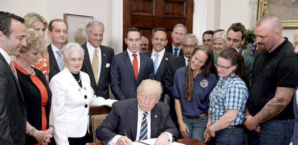 Firma. El presidente estadounidense, Donald Trump, al centro, firma la orden ejecutiva sobre capacitación laboral, ayer en la sala Roosevelt de la Casa Blanca en Washington.